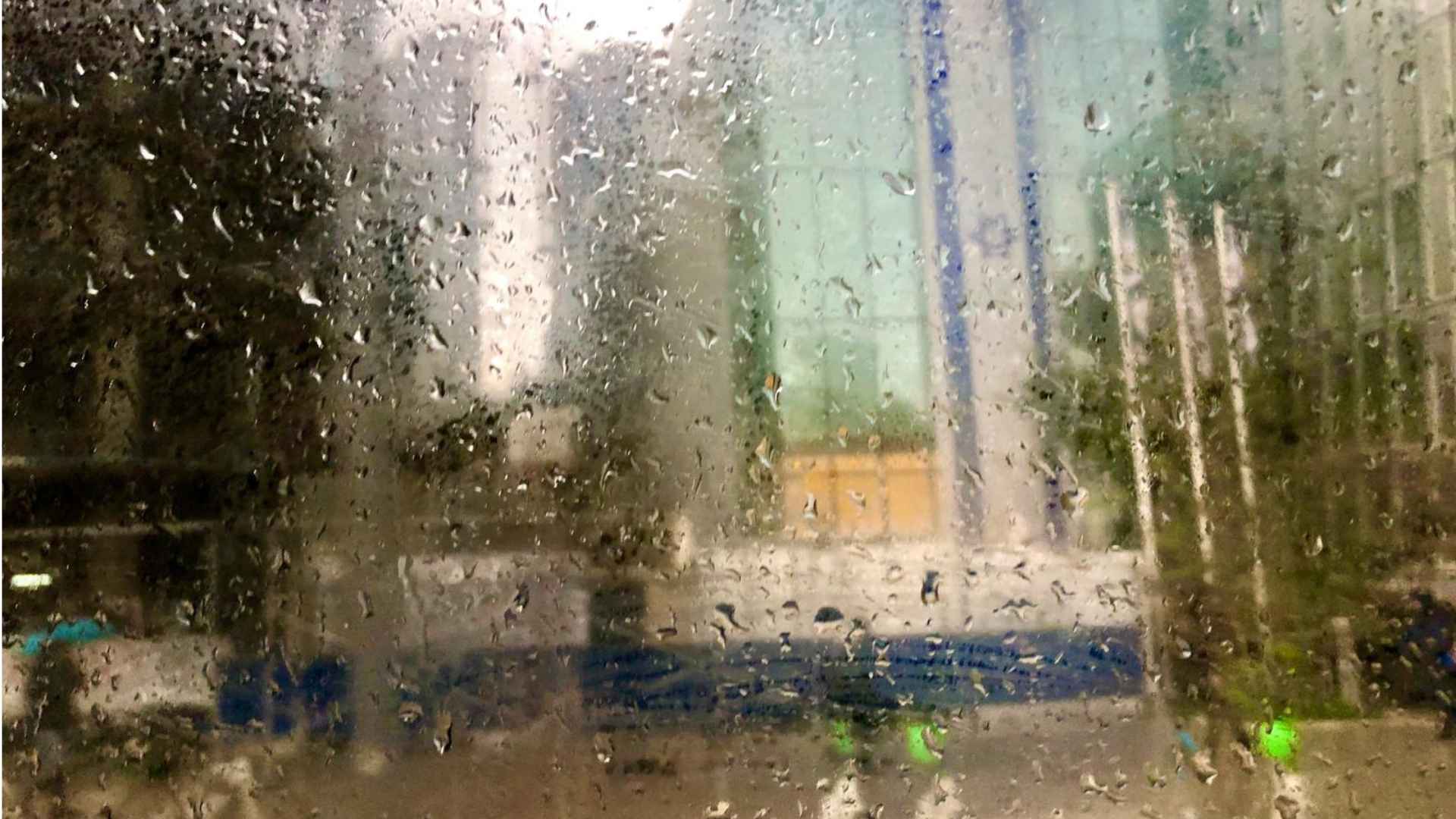 An Israeli flag on a building seen through a rain-covered window